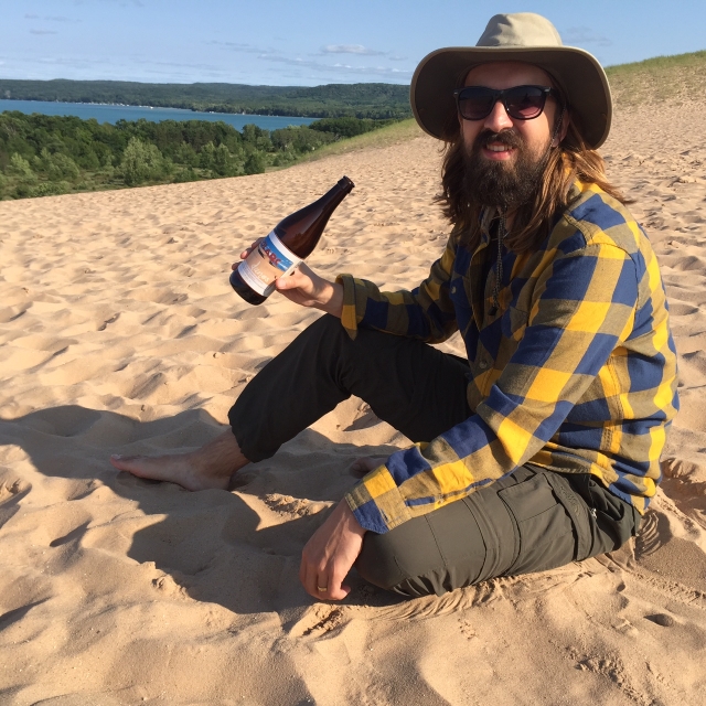 SoLArc Brewing co-founder and CalArts alumnus Archie Carey enjoying a bottle of 'Dunes' at Sleeping Bear Dunes National Park in Michigan. | Photo courtesy Archie Carey
